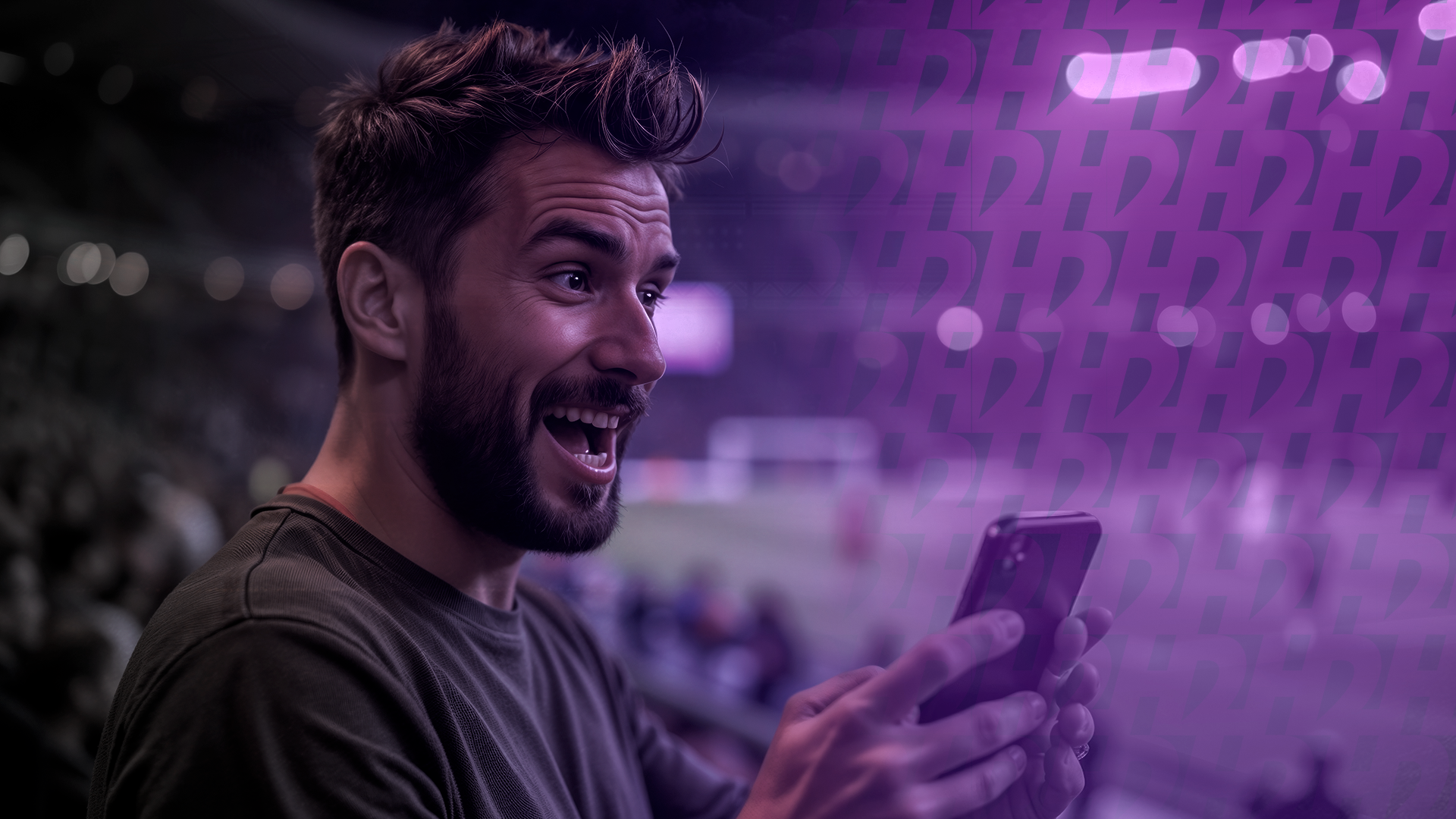 Um homem em um estádio de futebol animado olhando para o seu celular 